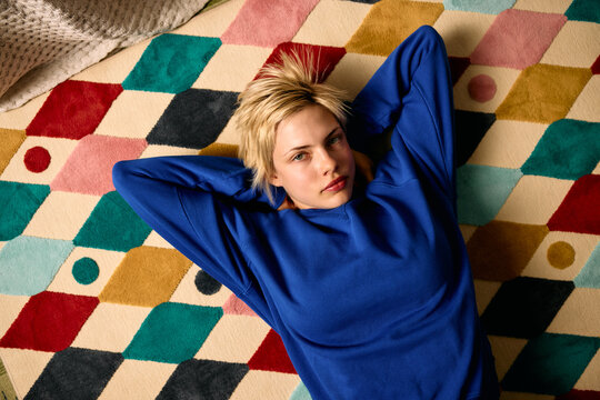 Handsome woman lying down on a colorful carpet
