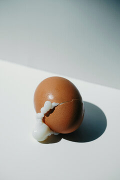 Brown Egg With Cracked Shell and Egg White on White Surface