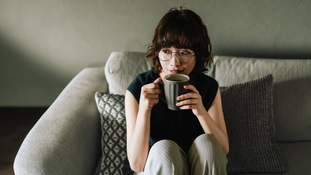 ソファに座って飲み物を飲む女性