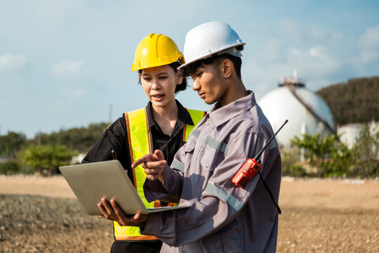 Engineers review a tablet at an outdoor industrial site