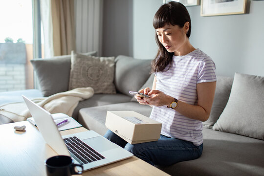 Woman tracking package on smartphone at home