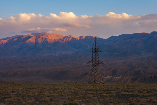 Electricity Pylon in Mountain Landscape at Sunrise or Sunset