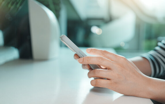 Smartphone in woman's hands, close up of female using mobile phone while sitting indoors, soft daylight and blurred background for communication, social media, online browsing and digital lifestyle.