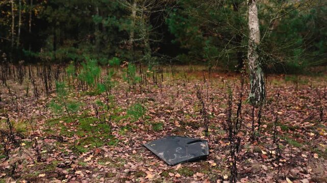 A destroyed military drone lies in a forest, highlighting environmental damage caused by the Russia-Ukraine war in Europe, including debris pollution and threats to the natural ecosystem.