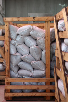 Bags of agricultural products are stored in wooden boxes in warehouse. Industrial storage of bagged goods. Storage shelving units