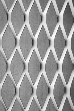 Metal mesh forms a geometric pattern on a concrete wall