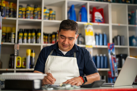 Auto parts shopkeeper writing an order at the counter, with supplies lining shelves