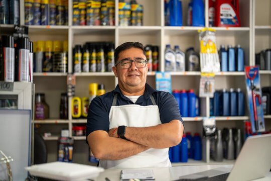 Auto parts shop owner standing behind the counter with arms crossed in an automotive store