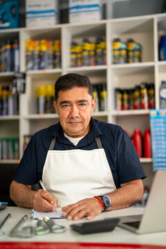 Shop owner writing an inventory checklist at the counter, with automotive products on shelves