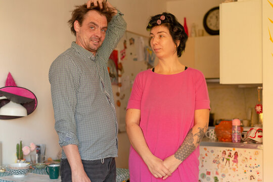 Man and woman standing together in kitchen interior, woman in pink top