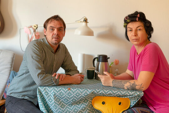 Man and woman sitting at kitchen table with thermos and smartphone