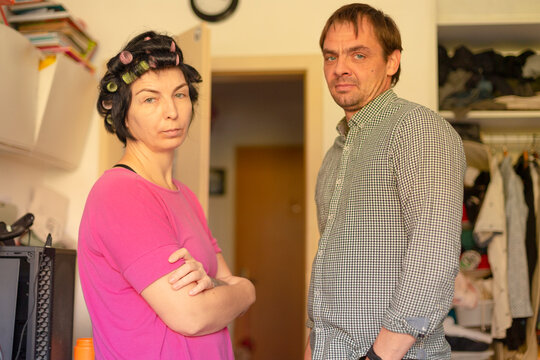 Woman with hair rollers and man standing in cluttered room together