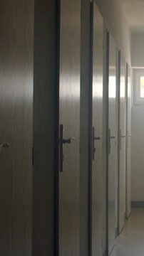 Row of closed school doors along narrow corridor with window light at,