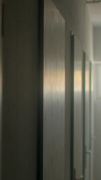 Empty school corridor with closed wooden classroom doors and soft sunr