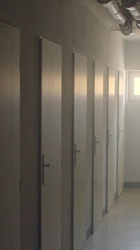 Narrow school corridor with row of closed doors in soft morning light