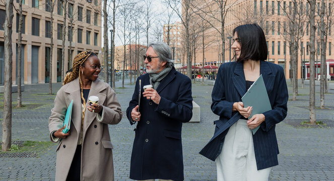 multiracial and diverse business adult group of people together in a winter morning outdoors at cityscape. Successful Entrepreneurs multigenerational teamwork in city urban scene 