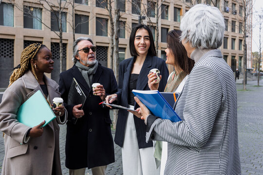 multiracial and diverse business adult group of people together in a winter morning outdoors at cityscape. Successful Entrepreneurs multigenerational teamwork in city urban scene 