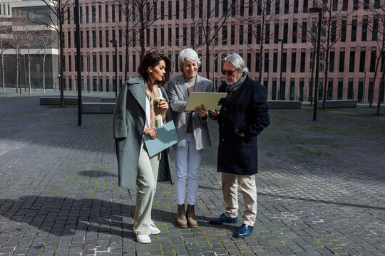 multiracial and diverse business adult group of people together in a winter morning outdoors at cityscape. Successful Entrepreneurs multigenerational teamwork in city urban scene 