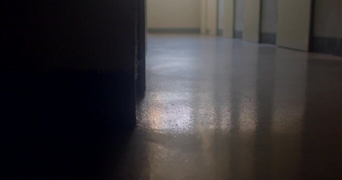 Low-angle school corridor with reflective floor and dark doorway, mood