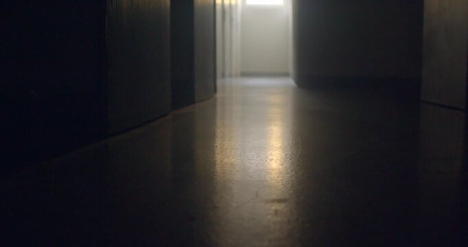 Low-angle school corridor with bright doorway and reflective polished,
