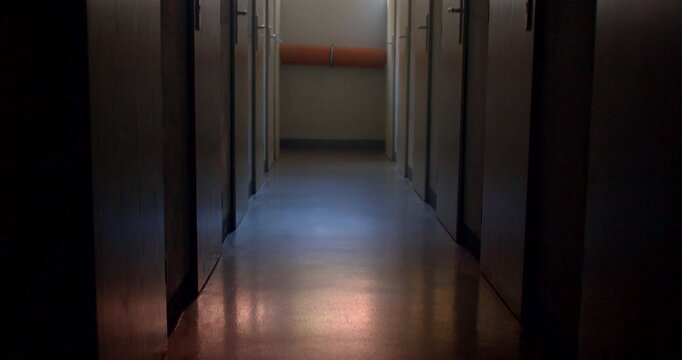 Dim school corridor with reflective floor and high window light toward
