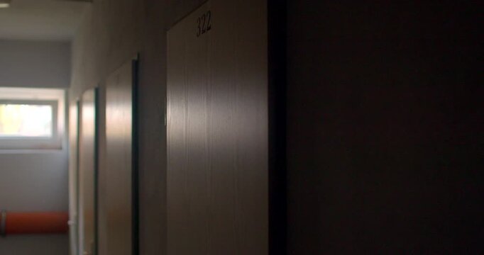 Dim school corridor with numbered classroom doors and soft window back