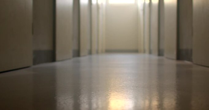 Low-angle polished school corridor reflecting morning light toward far