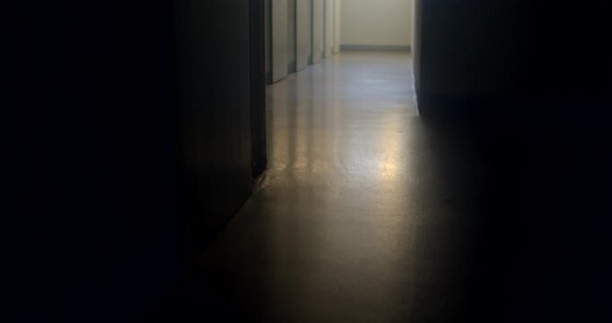Low-angle dark corridor with distant daylight reflecting on polished s