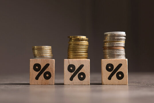 Discount concept. Wooden cubes with percent signs and stacked coins on table