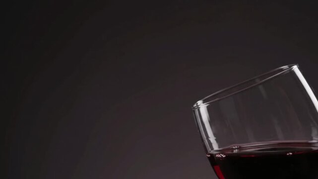 Macro shot of static crystal wine glass rim with subtle red wine swirl, dark minimalist copy space for luxury hospitality background.