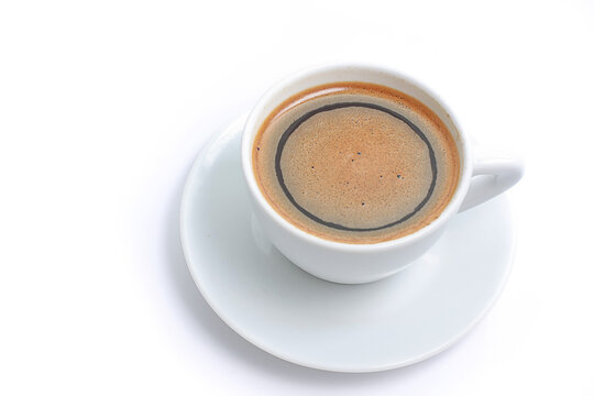 High angle close up of a white porcelain cup with fresh black coffee and foam isolated on white background