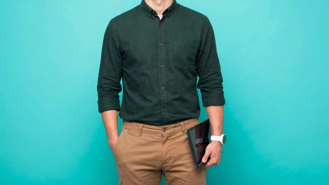 Unrecognizable young professional holding a digital tablet and wearing a smartwatch. Male entrepreneur in casual attire posing in a studio. Wide banner with copy space for advertising