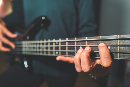 Woman's Hand on a Bass Guitar Fretboard with Neck in View