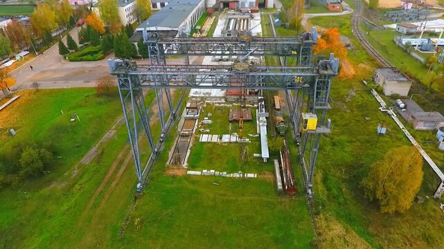 Bridge cranes storage yard aerial view autumn. Orbit shot heavy machinery site.