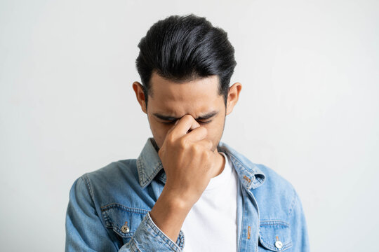 Young man has a strong headache isolated on background.