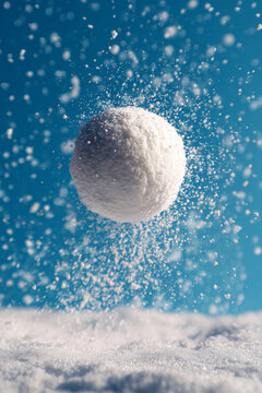 Snowball Rising through Falling Snowflakes in Crisp Winter Air with Bright Blue Sky and Sparkling Cold Atmosphere