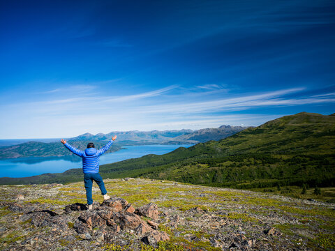 Woman with arms raised overlooking a lake in Skilak Lake