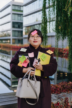Overworked businesswoman carrying notes outside office building