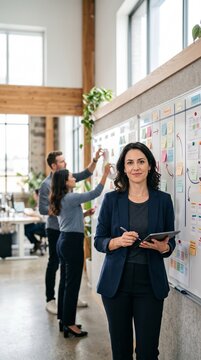 Businesswoman holding tablet beside collaborative planning board in bright modern office interior