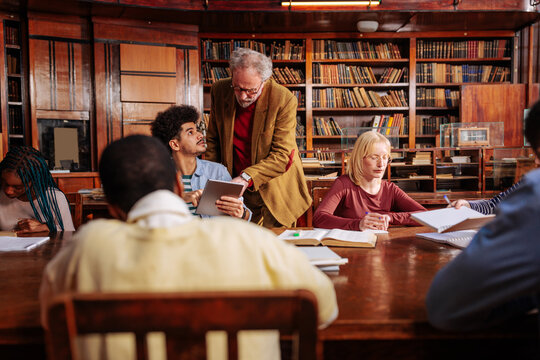 Student studies with a professor using a tablet in a historic library