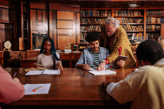 Library study group: student learning with a professor at a historic table