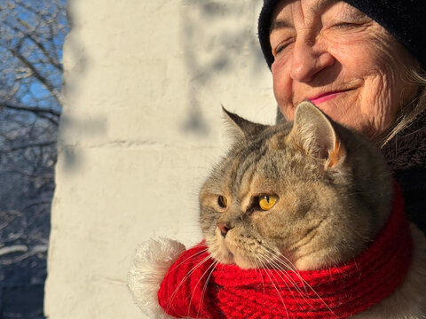 Happy elderly lady with her beloved cat in winter close up
