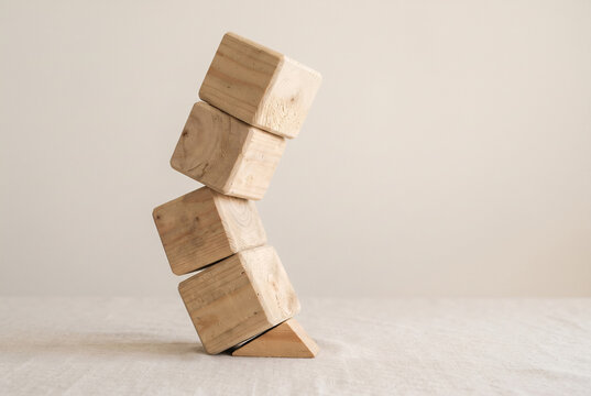 Leaning tower of wooden blocks held up by one small wooden wedge