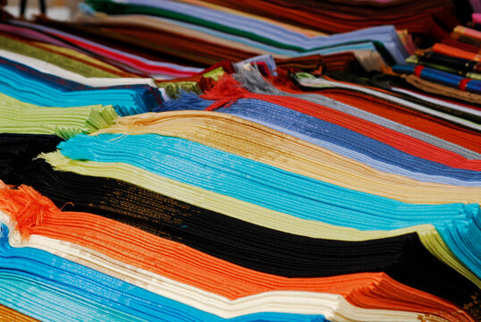 Rows of folded colorful fringed scarves at a market stall, Imbabura, Otavalo, Ecuador