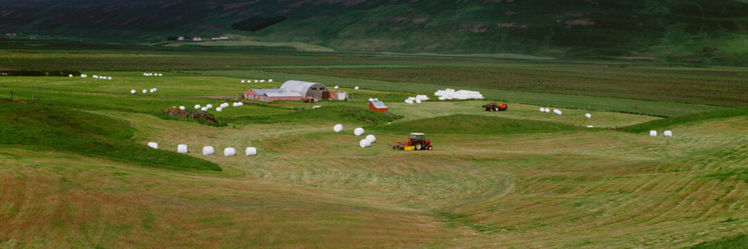 Farm landscape with hay bales and tractors working