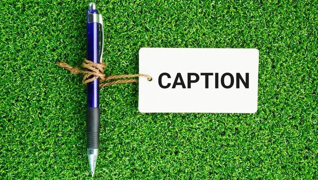 Pen and paper tags with caption words. short piece of text that accompanies an image, video, article, or legal document to explain, describe, or add context.