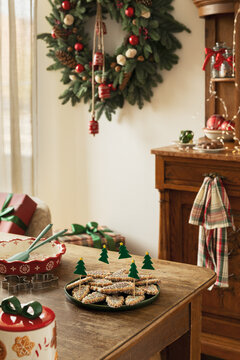 Festive Christmas table setting with homemade cookies, holiday wreath, and wrapped gifts in a cozy home interior during the winter holiday season