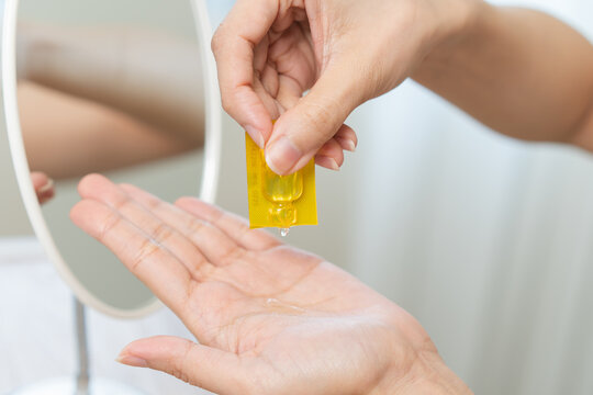 Close up of woman hand squeezing single dose yellow cosmetic ampoule serum