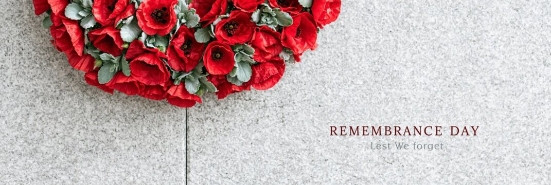 Red poppy wreath on stone memorial wall for Remembrance Day. Community tribute for veterans and fallen soldiers, honor and reflection concept