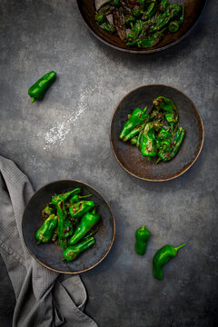 Dark bowls contain fried Pimientos de Padron with coarse sea salt